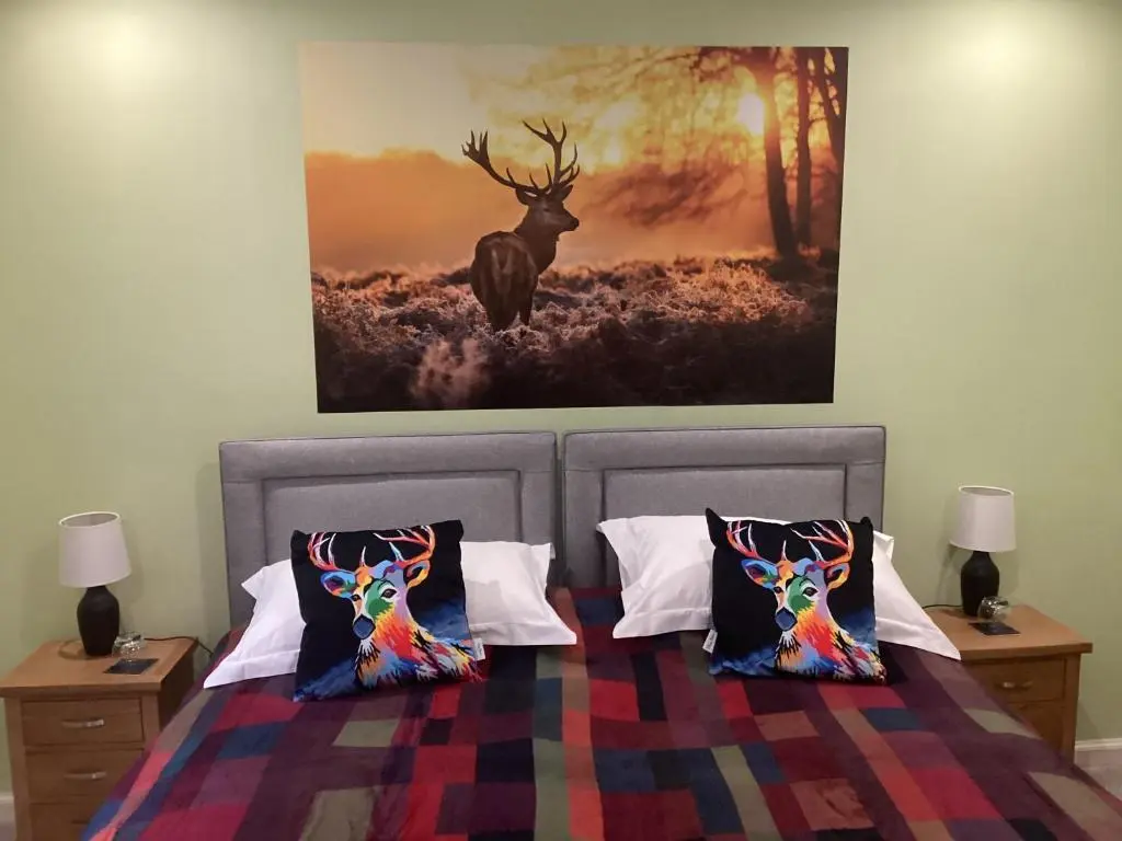 a bedroom with a bed with a painting on the wall at Taigh Sealladh F\u00e8idh B&B in Fort Augustus