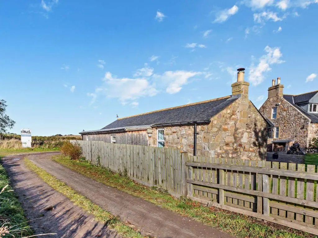 an old stone house with a fence and a dirt road at 1 Bed in Elgin 32129 in Burghead
