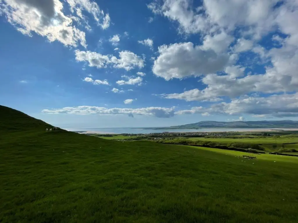 a green field with a blue sky and clouds at The Highlander in Tain