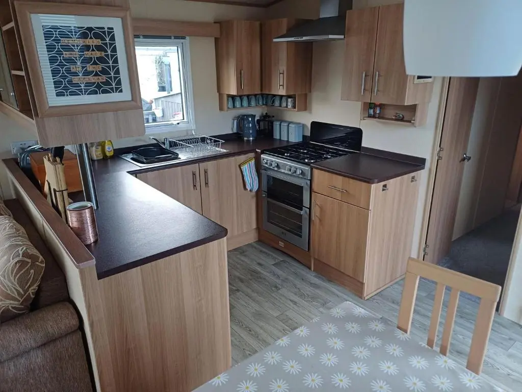 a small kitchen with wooden cabinets and a stove at The Highlander in Tain