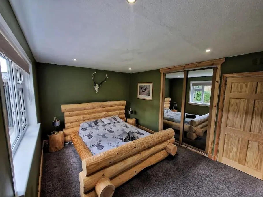 a bedroom with a large wooden bed and a mirror at Town centre house, Hot tub, Cinema room and Gym in Aviemore