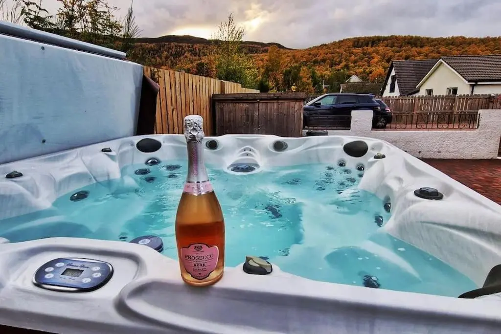 a bottle of beer sitting in a hot tub at Town centre house, Hot tub, Cinema room and Gym in Aviemore
