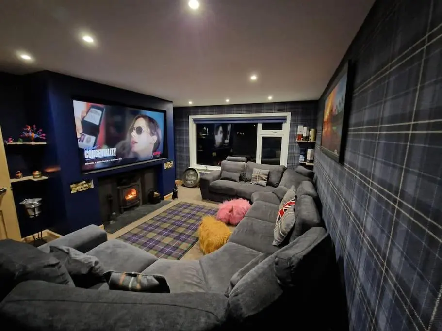a living room with a couch and a tv at Town centre house, Hot tub, Cinema room and Gym in Aviemore