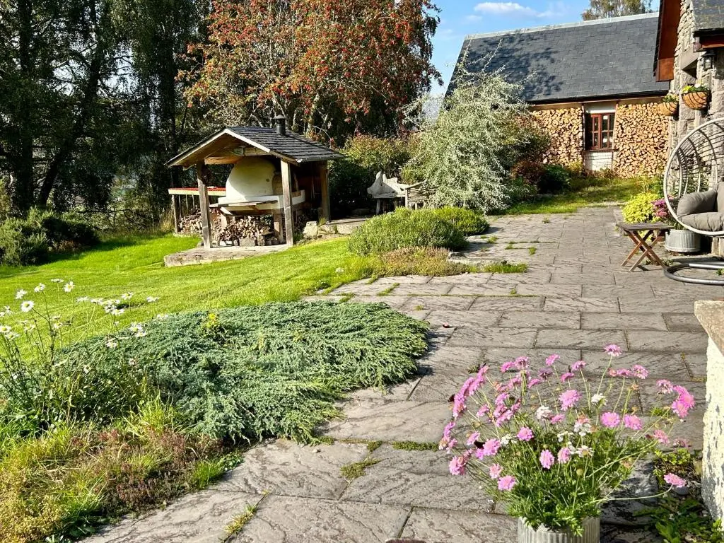 a garden with a stone path and flowers and a building at Drumguish Cottage in Kingussie