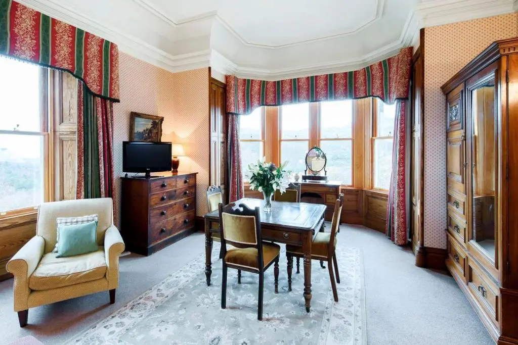 a dining room with a table and chairs and a television at Caledonian Lodge in Croick