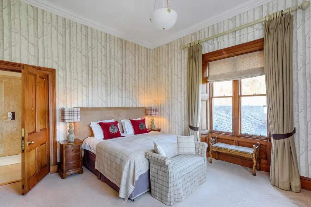 a bedroom with a bed and a chair and a window at Caledonian Lodge in Croick