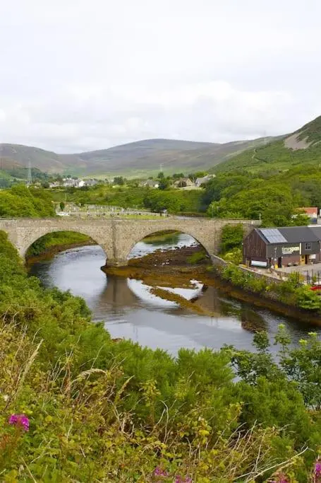 a stone bridge over a river in a town at Comfortable 4 bed Home, Valhalla, Helmsdale in Helmsdale