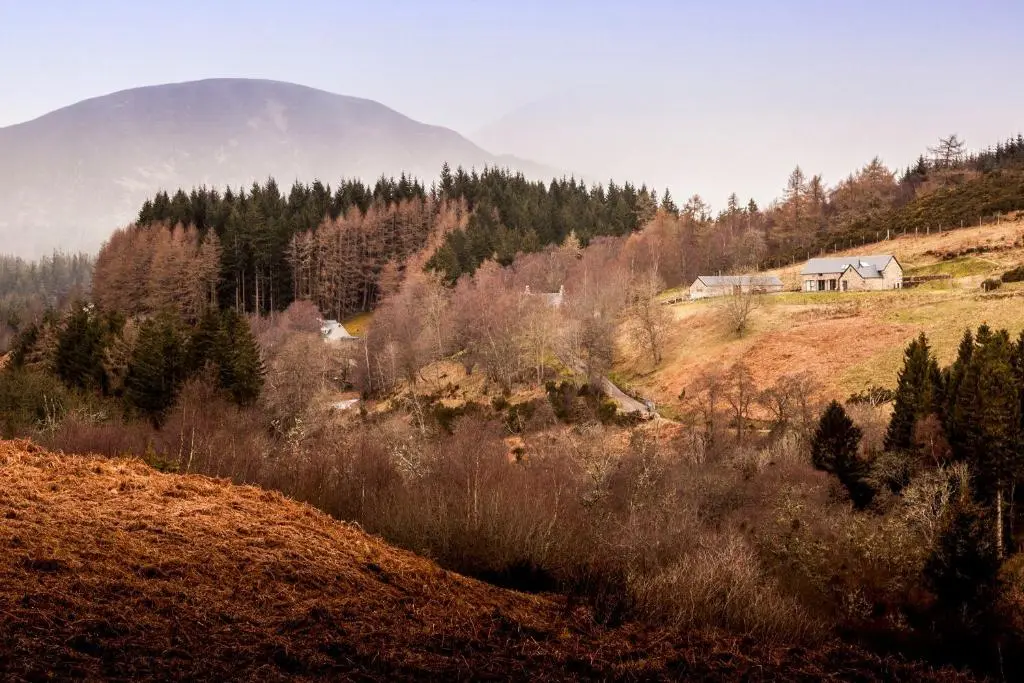a house on a hill with a mountain in the background at Greenhill Cottage in Evanton