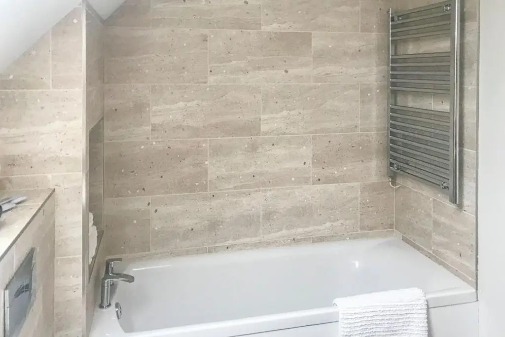 a bath tub in a bathroom with a tile wall at Greenhill Cottage in Evanton