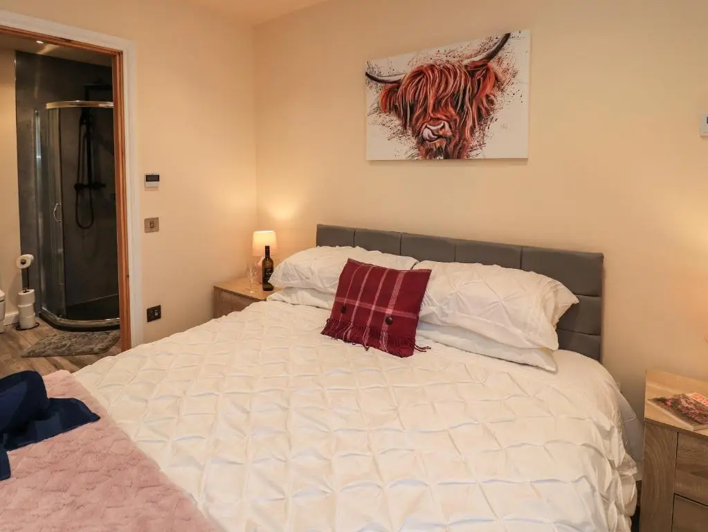 a bedroom with a white bed with a red pillow at Pine Marten in Dornoch