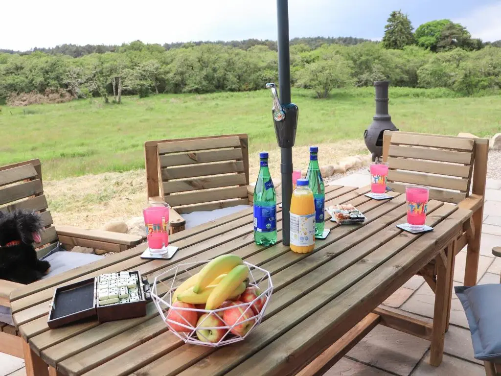 a wooden picnic table with a basket of fruit and drinks at Pine Marten in Dornoch
