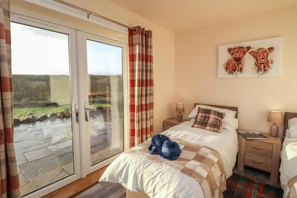 a bedroom with a bed and a sliding glass door at Red Squirrel in Dornoch