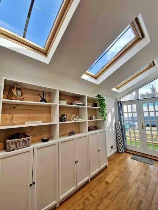 a large room with white cabinets and skylights at Cullen Seaside Cottage in Cullen