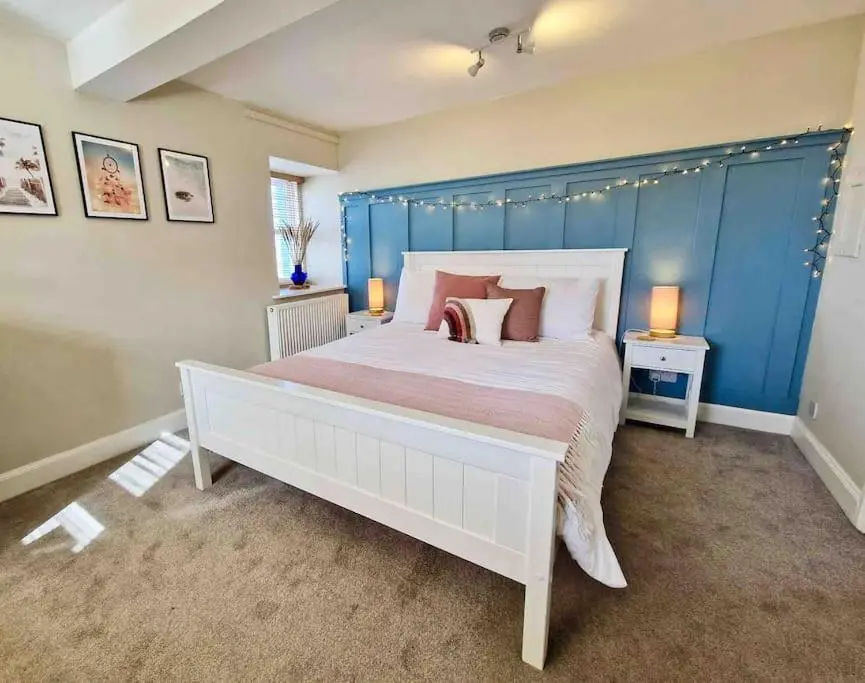 a bedroom with a large white bed with pink pillows at Cullen Seaside Cottage in Cullen