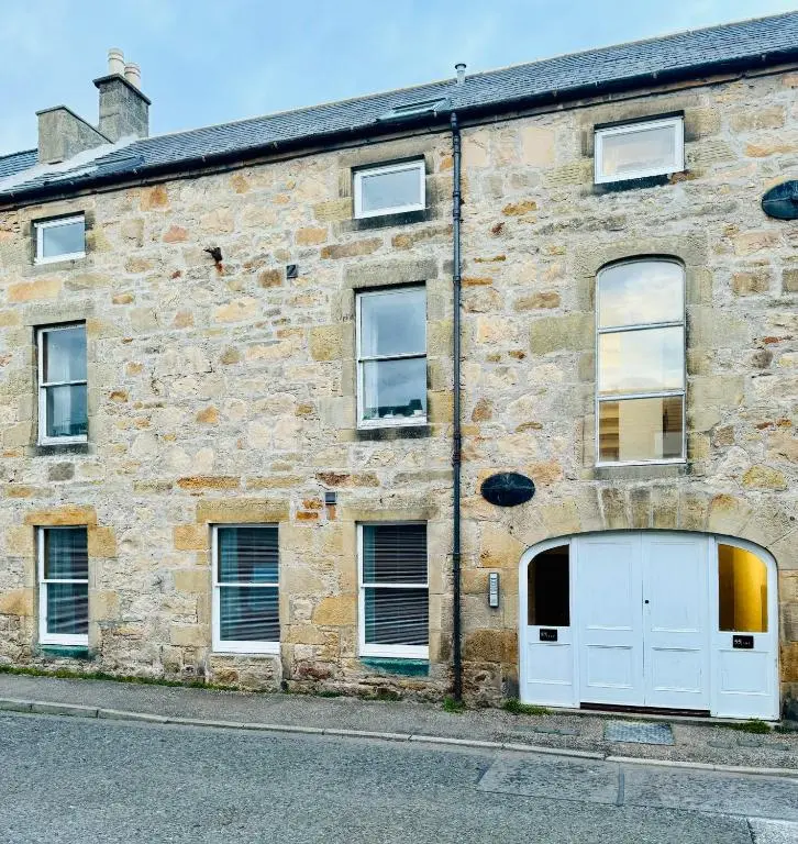 an old stone building with a white garage at Firth View, Burghead in Burghead