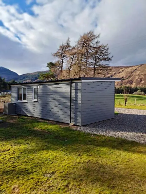 a small house in the middle of a field at Rowan Bank Retreat in Fort Augustus