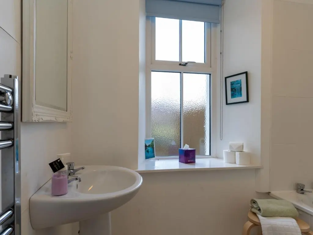 a white bathroom with a sink and a window at Holiday Home Railway House by Interhome in Aviemore
