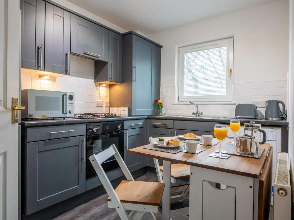 a kitchen with blue cabinets and a table with drinks on it at Apartment Number 39 by Interhome in Inverness
