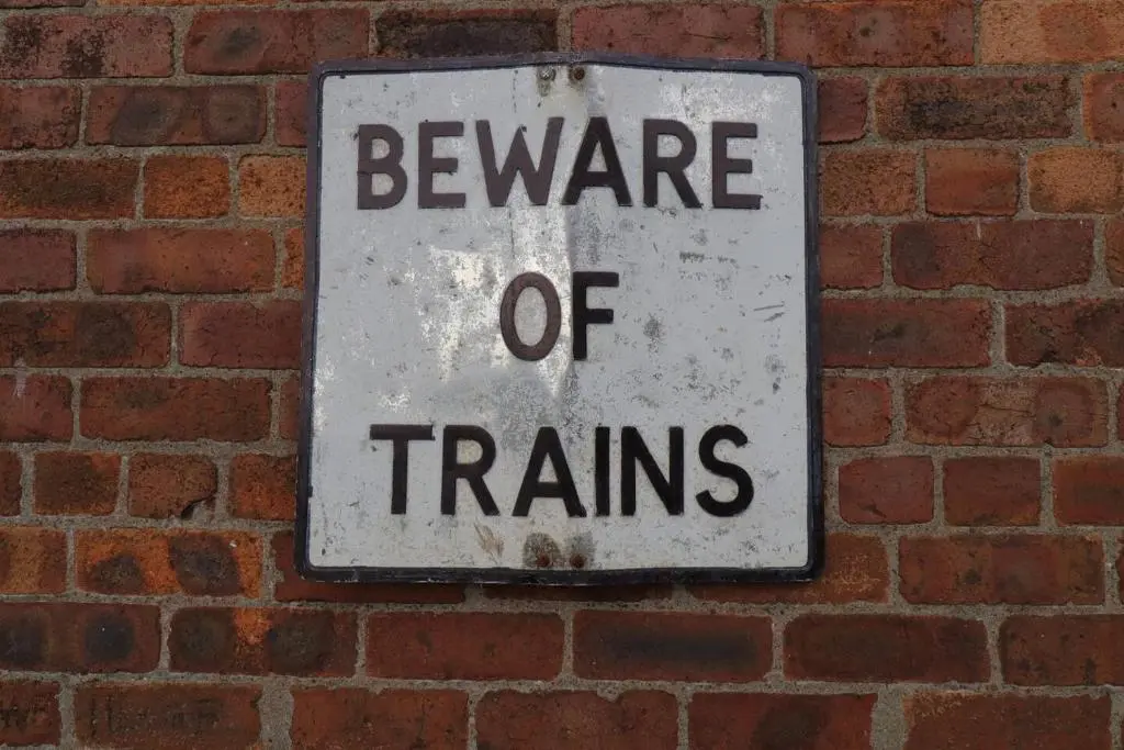 a beware of trains sign on a brick wall at Crossing Cottage, Brora in Brora