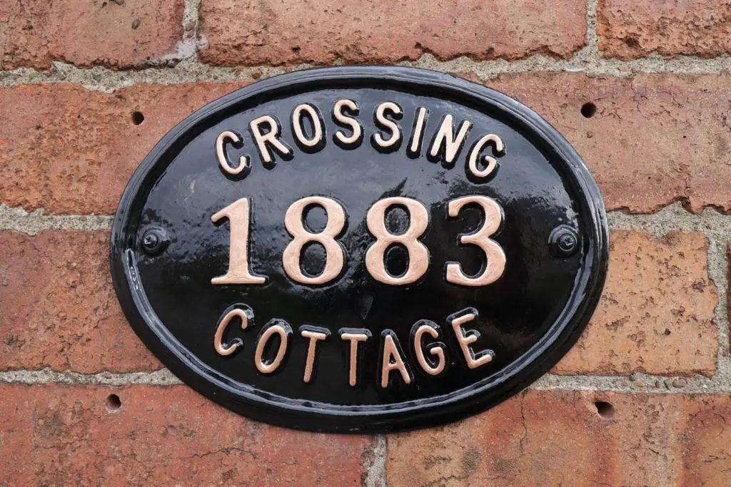 a sign on the side of a brick wall at Crossing Cottage, Brora in Brora