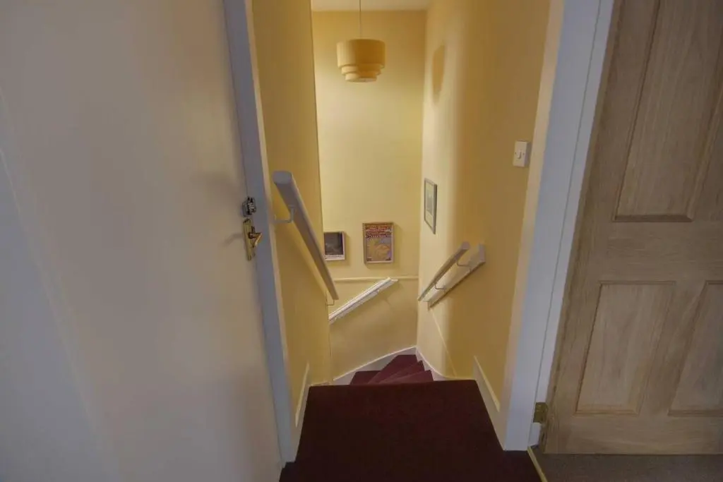 a hallway with a stairway with a door and a stair case at Crossing Cottage, Brora in Brora