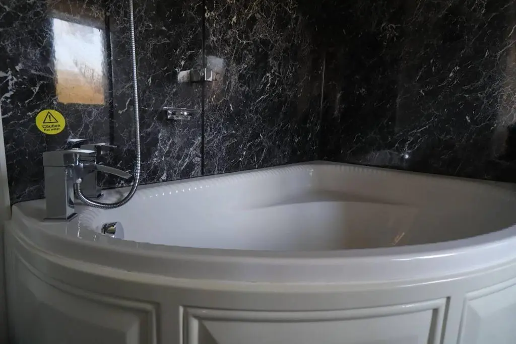 a white bath tub with a shower in a bathroom at Crossing Cottage, Brora in Brora