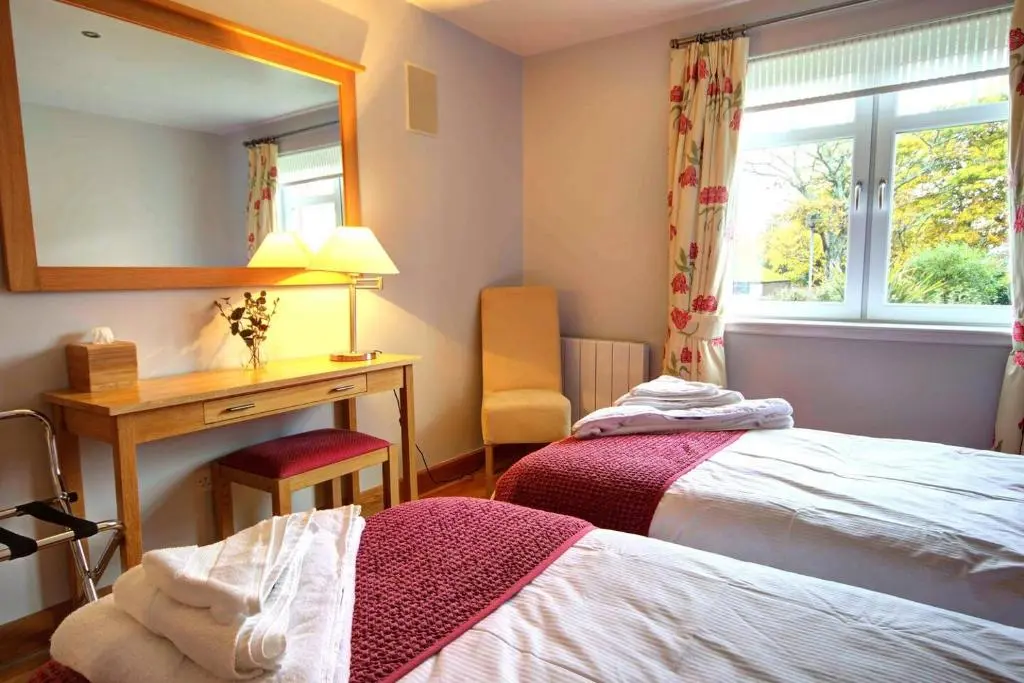 a bedroom with a bed and a desk and a mirror at No1 The Links Apartment, Brora in Brora