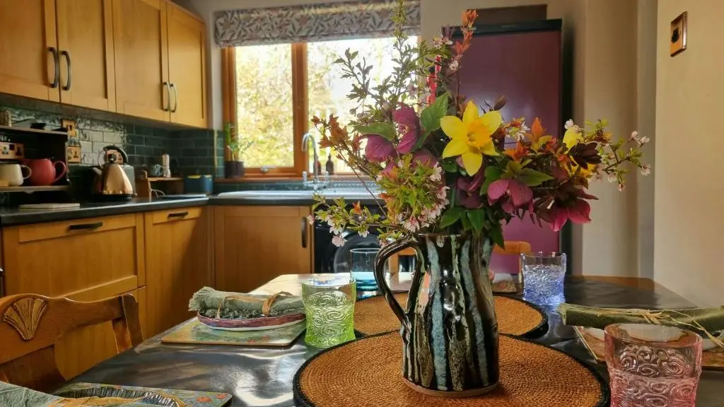 a vase of flowers on a table in a kitchen at Luxury 3 Bedroom Cottage - Sleeps 6 in Tomintoul