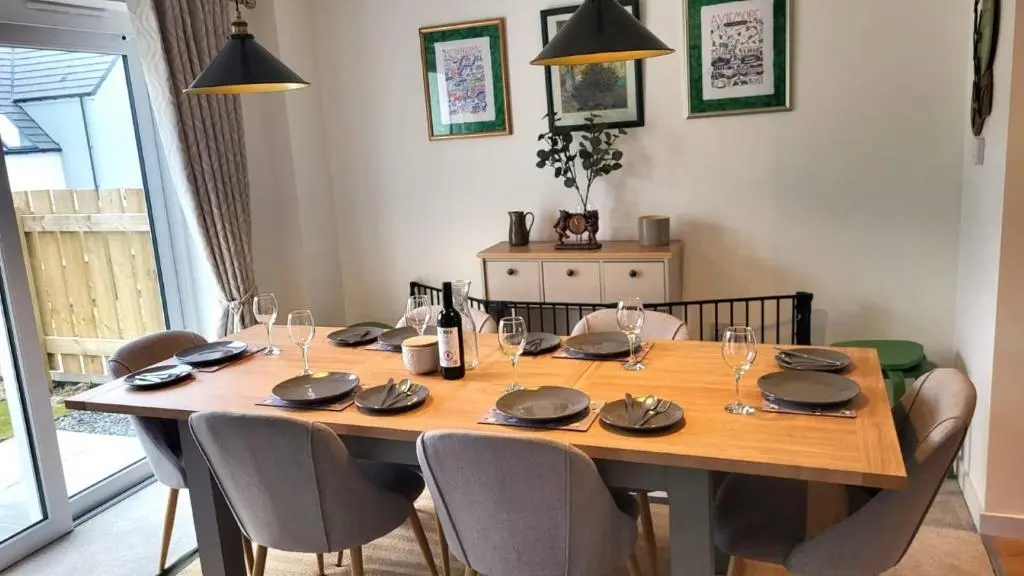 a dining room table with chairs and a wooden table with wine glasses at Insch House in Kincraig