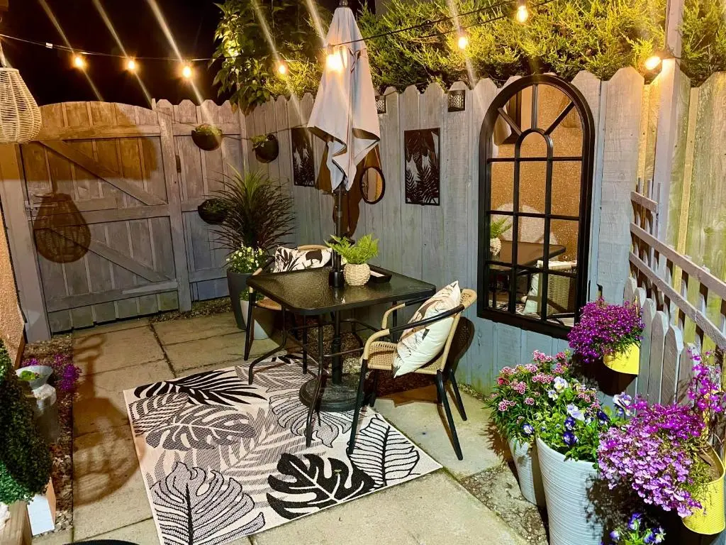 a patio with a table and chairs and flowers at Findon nook in Culbokie
