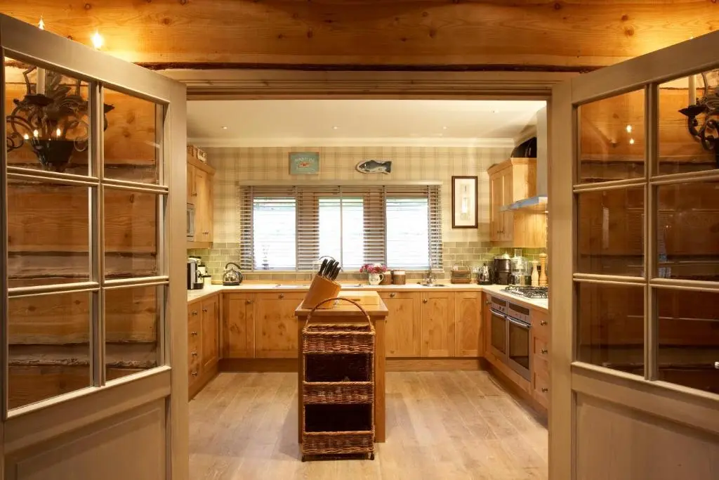 a large kitchen with wooden cabinets and wooden floors at Ness Castle Lodges in Inverness