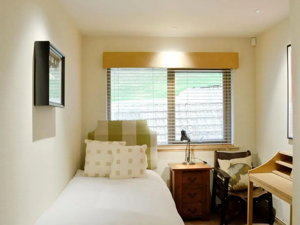 a bedroom with a bed and a desk and a window at Ness Castle Lodges in Inverness