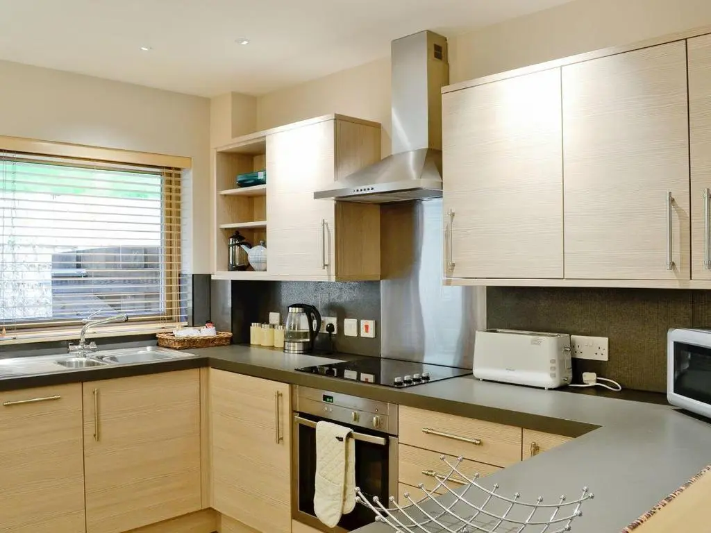 a kitchen with wooden cabinets and a stove top oven at Ness Castle Lodges in Inverness