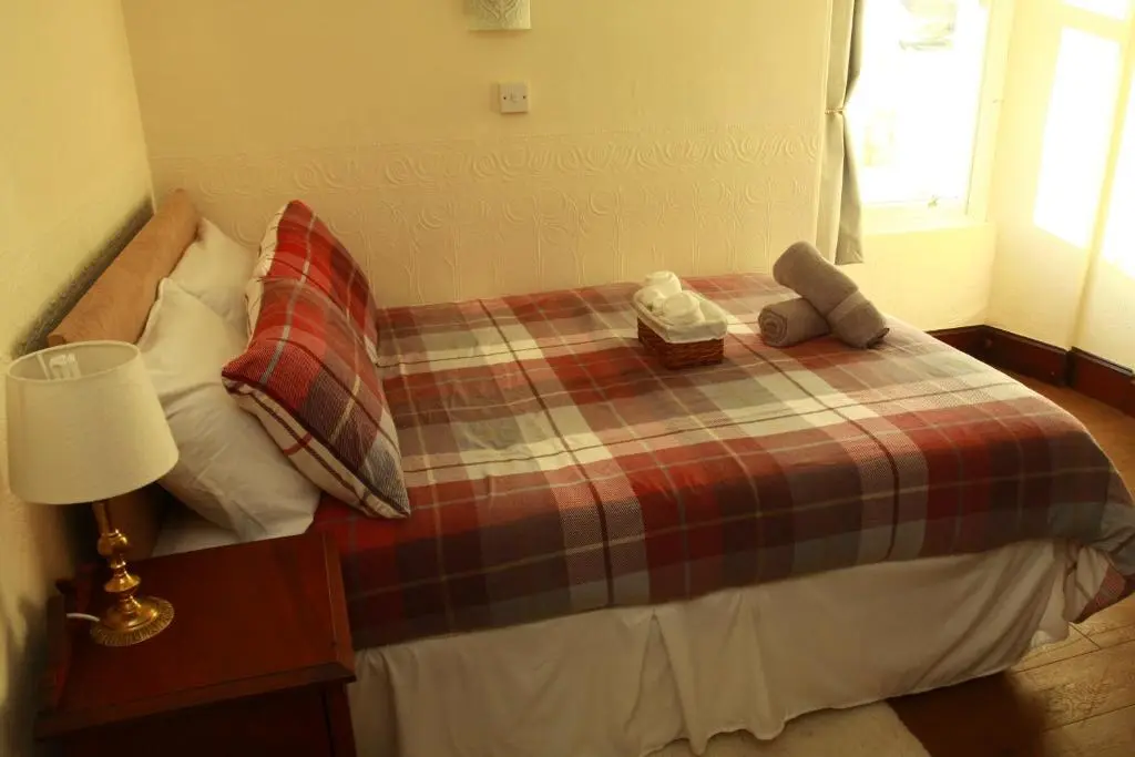 a bed with a plaid blanket and a stuffed animal on it at The Retreat Hotel in Strathpeffer