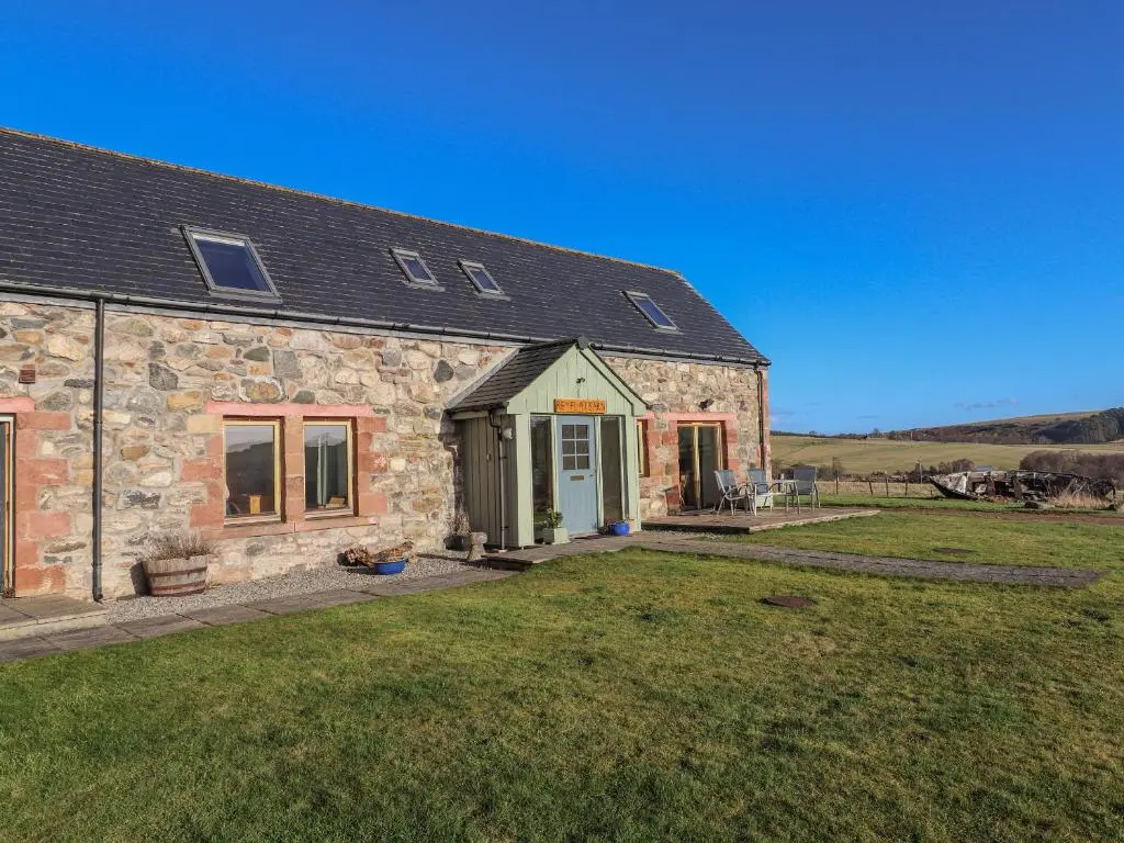a stone house with a green door and a yard at Reyflat Barn in Fortrose