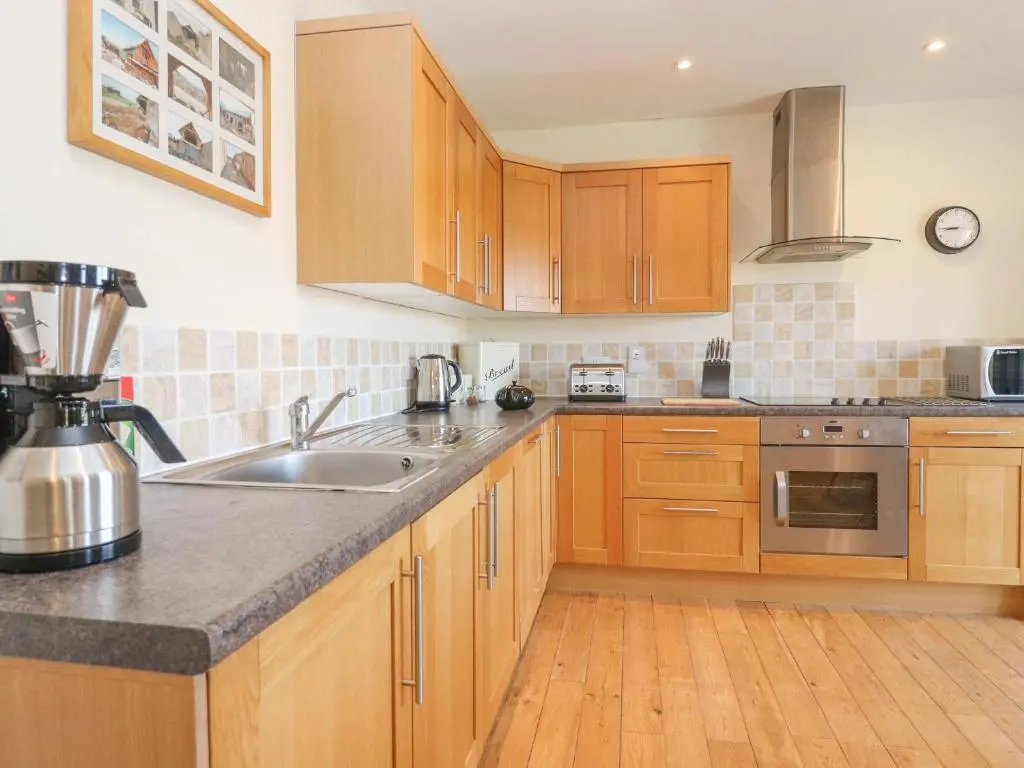 a kitchen with wooden cabinets and a sink at Reyflat Barn in Fortrose