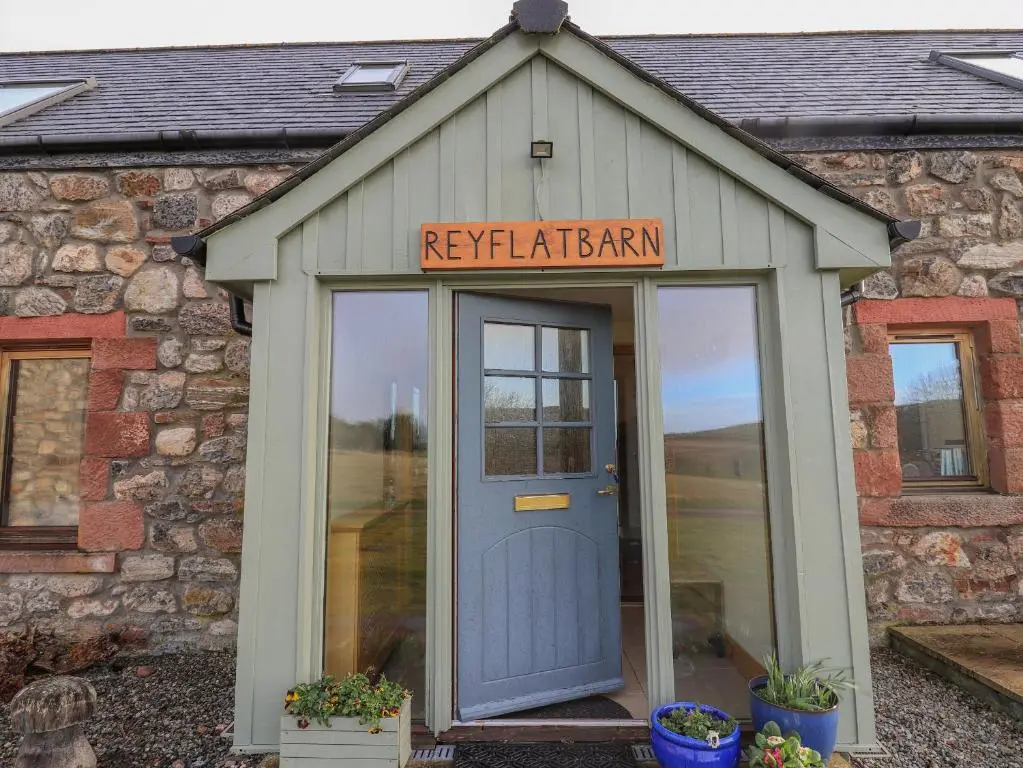 a building with a blue door and a sign on it at Reyflat Barn in Fortrose