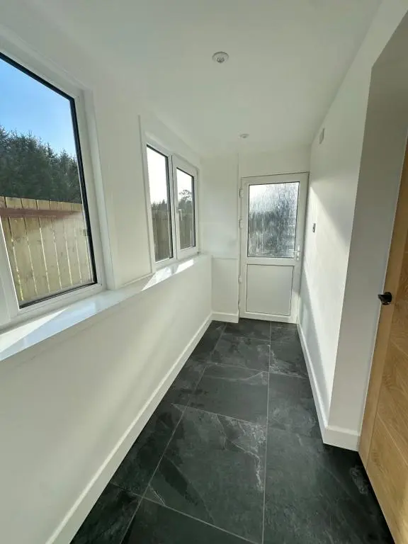 an empty room with two windows and a tiled floor at Smiddy Cottage Bauds in Buckie