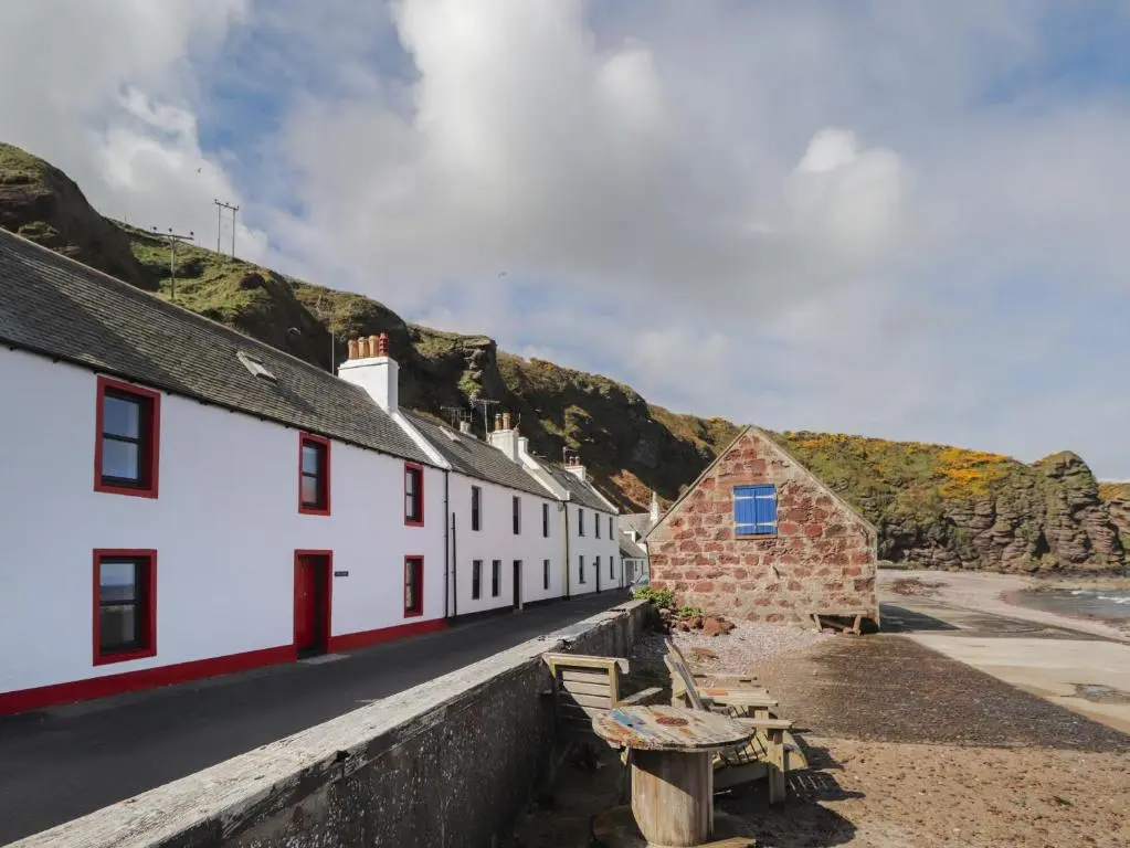 a row of white buildings on the beach with mountains at The Laurels in Fraserburgh