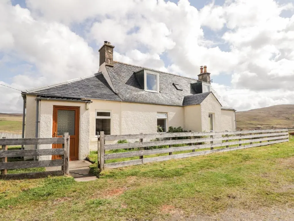 a white house with a fence in a field at Loubcroy Farm House in Lairg