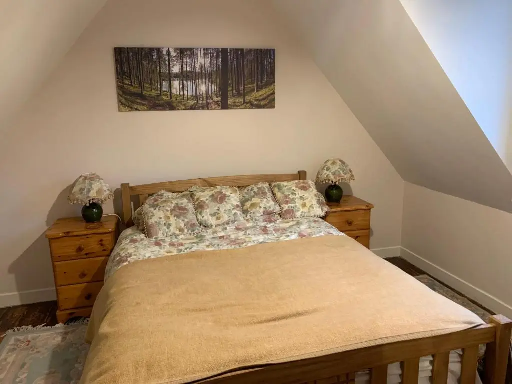 a bedroom with a bed and two dressers in a attic at Loubcroy Farm House in Lairg
