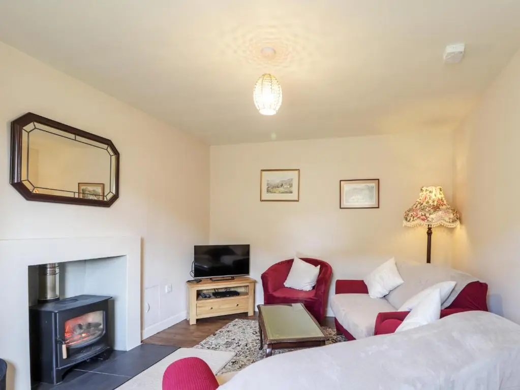 a living room with a couch and a fireplace at Loubcroy Farm House in Lairg