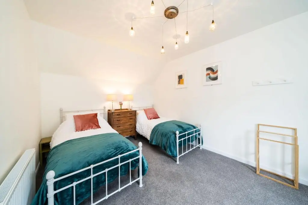 two beds in a room with white walls at The Corner House in Hopeman