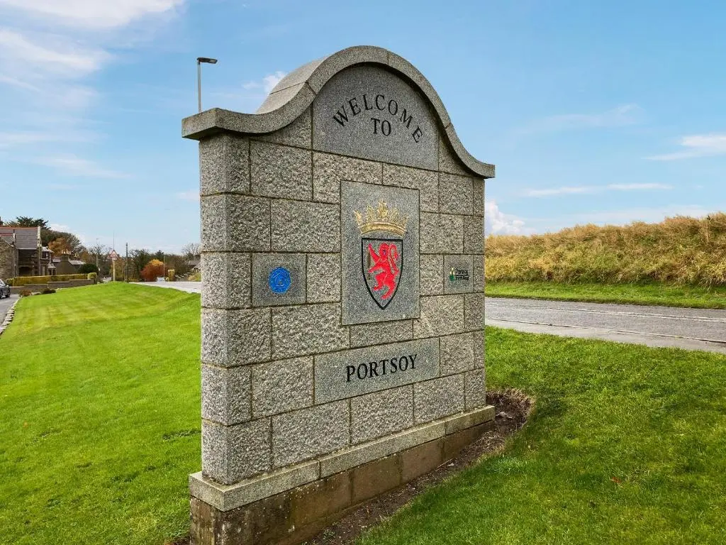 a stone monument with a crest on it in a field at Mains Of Durn Cottage, in Banff