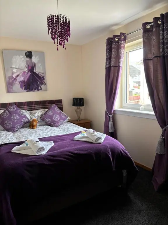 a bedroom with a purple bed and a window at Cameron apartment Loch Ness in Fort Augustus