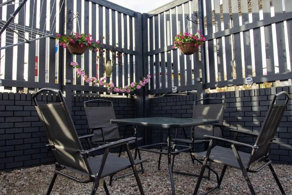 a table and chairs on a patio with a fence at Cameron apartment Loch Ness in Fort Augustus
