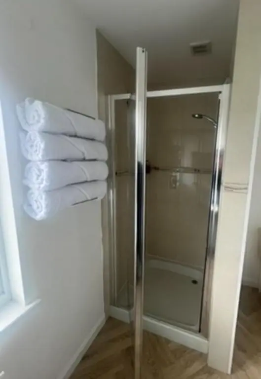 a bathroom with a shower and a stack of towels at Eldon Lea in Strathpeffer