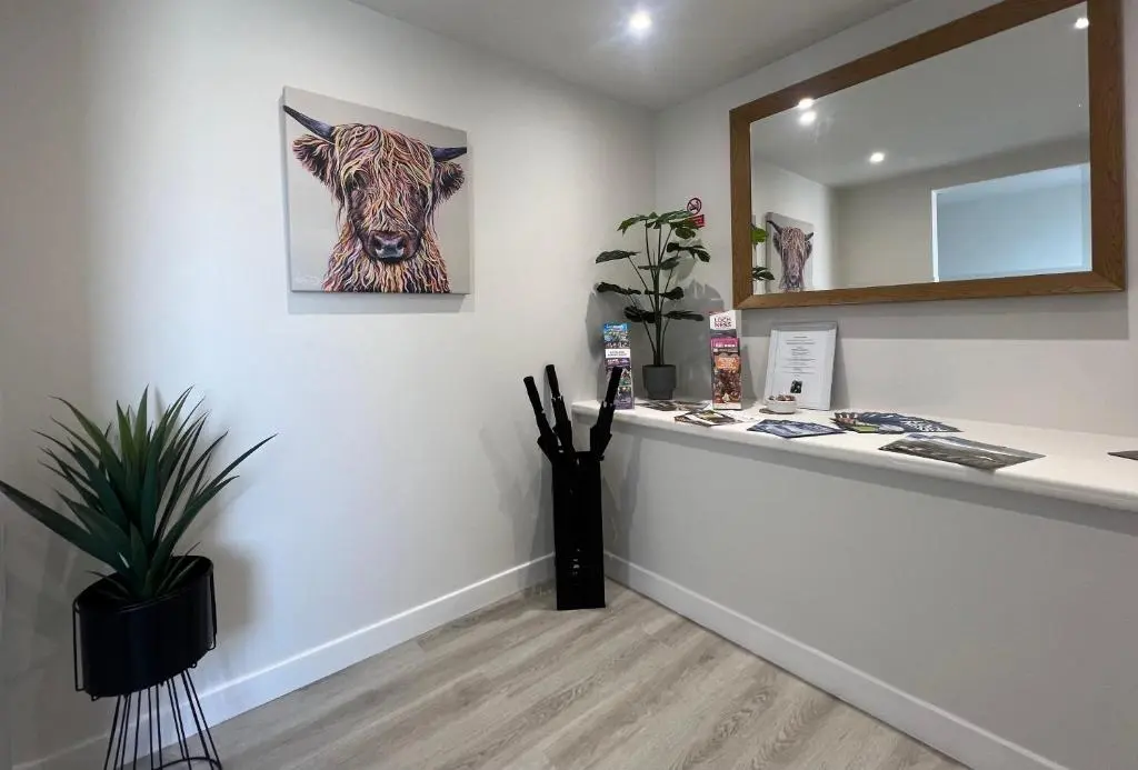 a reception desk with a picture of a cow on the wall at Eldon Lea in Strathpeffer