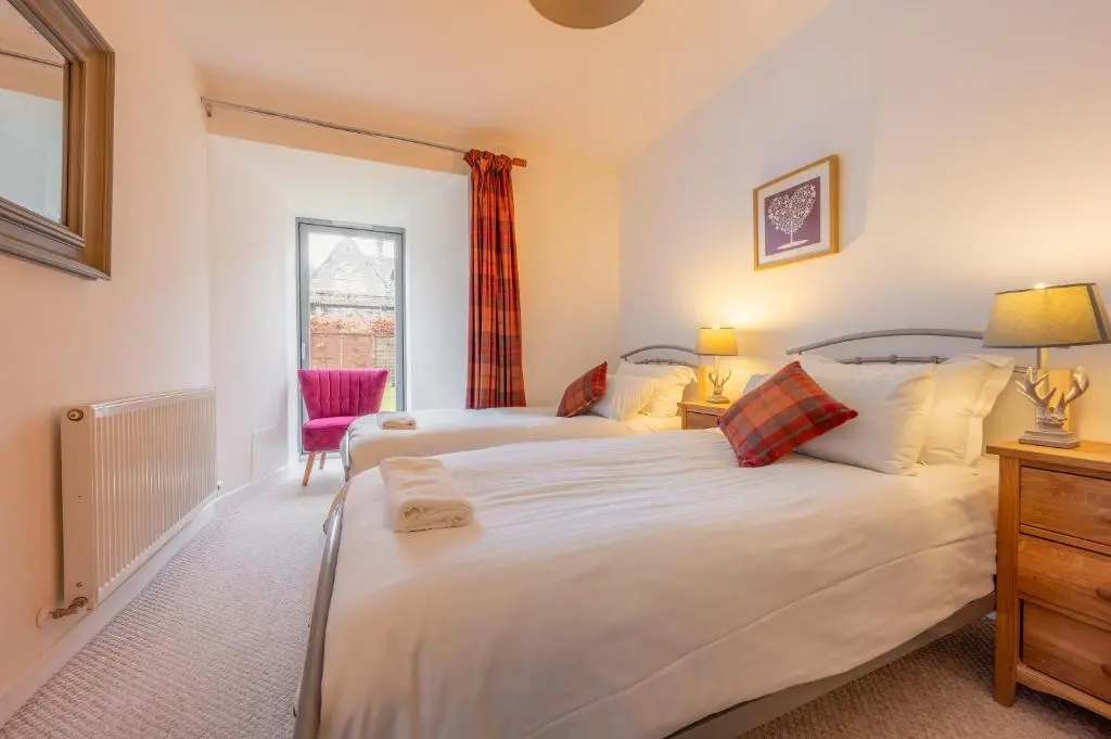 a bedroom with two beds and a window at Abbey Church 9 The Nave 2 bedroom Luxury Self catering apartment in Historic Abbey in Fort Augustus