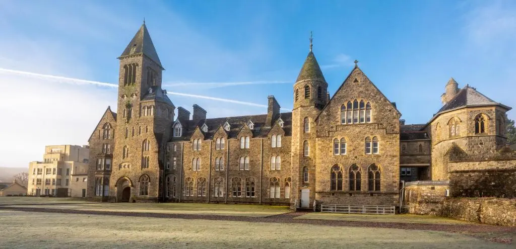 a large brick building with a tower on top at AC19 Lower North Aisle - Luxury Self Catering 2 Bedroom Apartment in Fort Augustus